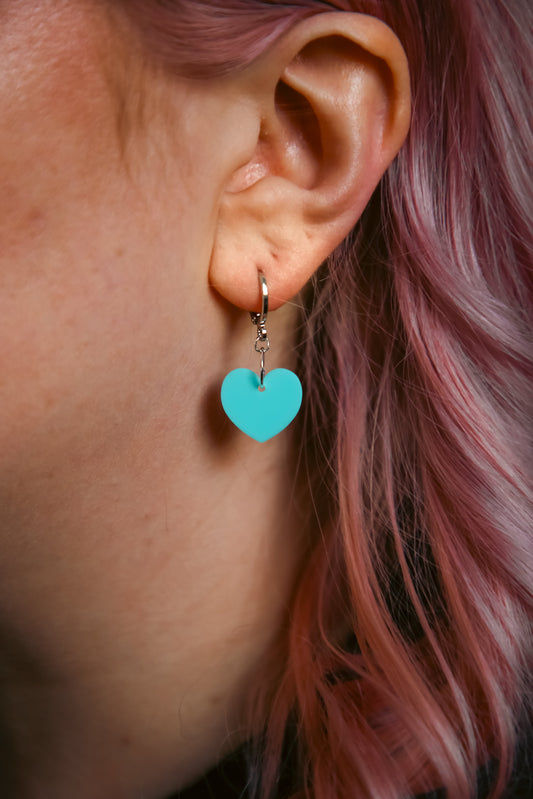 A pastel blue heart acrylic earring on an ear