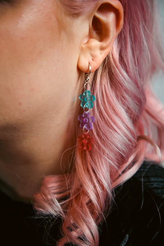 blue, purple and pink glittery transparent flower earring against purple hair