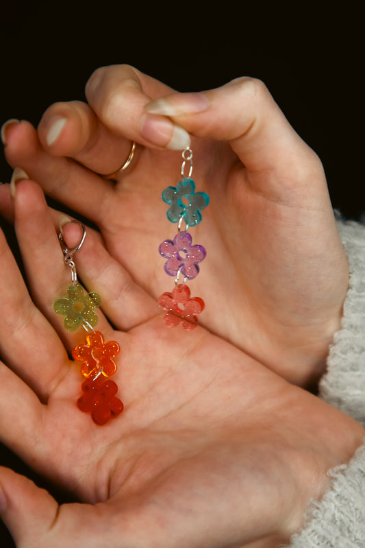 multicoloured glittery transparent flower acrylic earring being held by hands