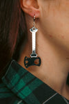 black blade and reflective silver handle axe acrylic earrings against brown hair
