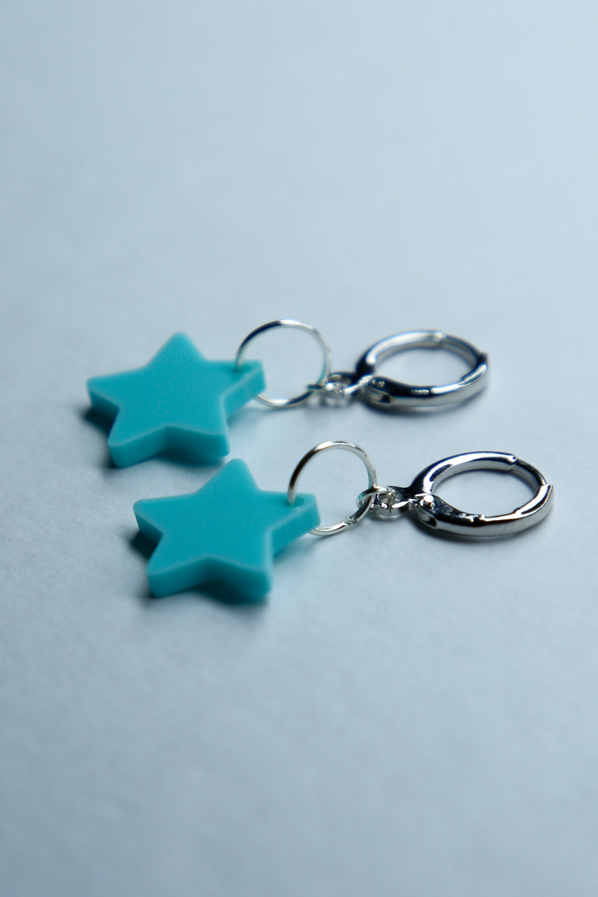 A pair of pastel blue flower acrylic earring on a blue background