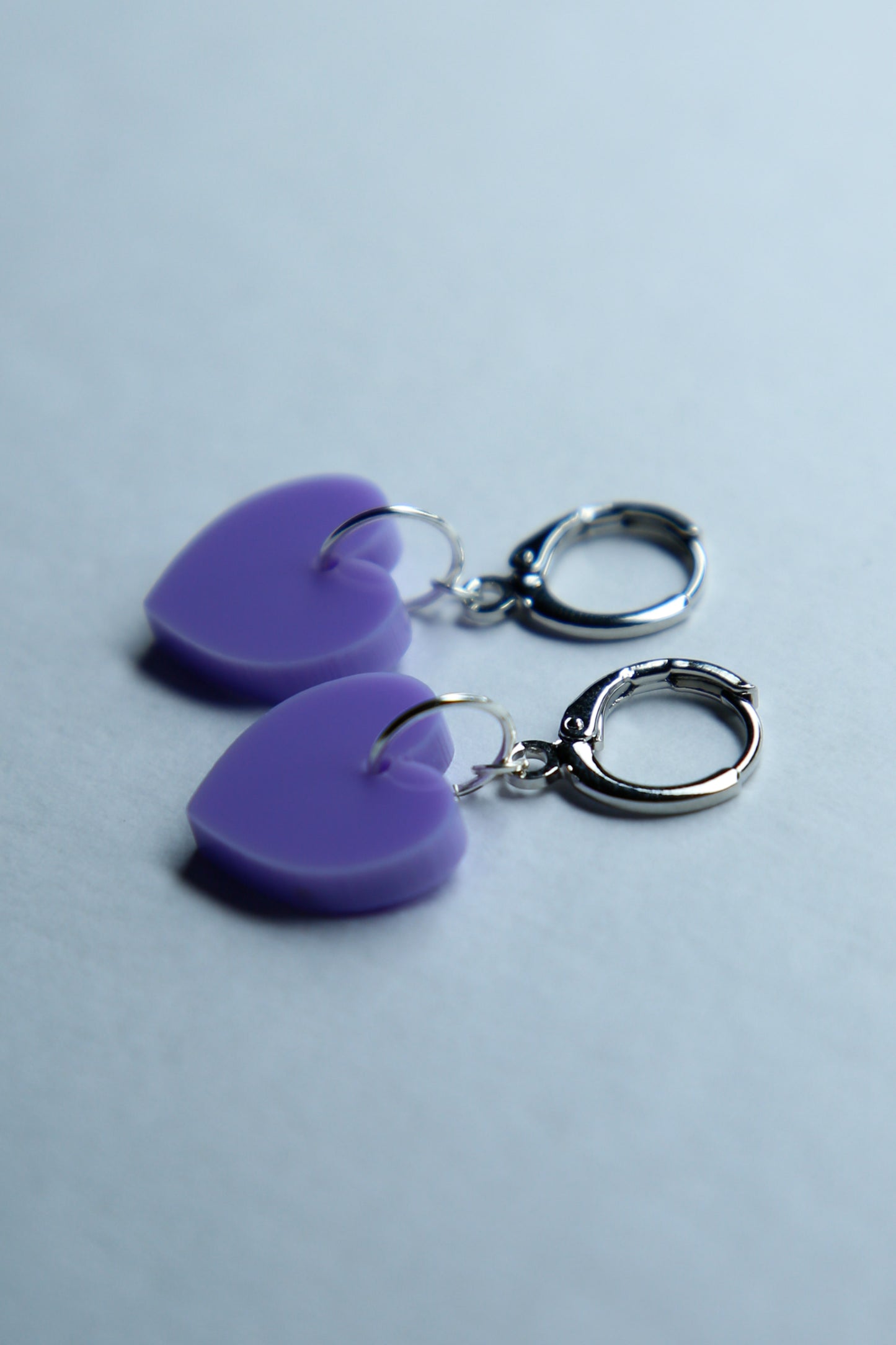 A pair of pastel purple star acrylic earring on a blue background