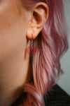 A pink transparent glitter heart acrylic earring on an ear