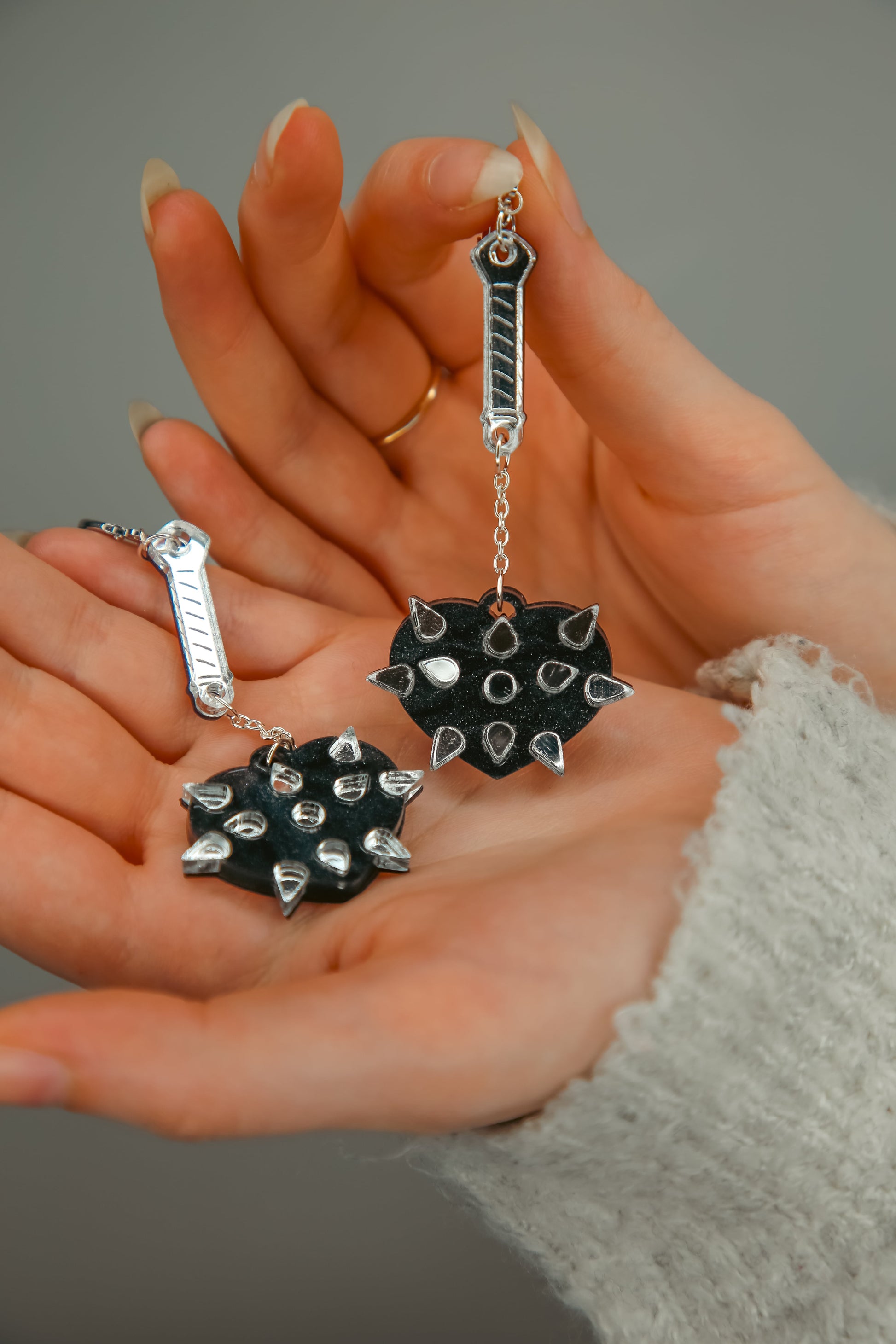 A pair of mace weapon acrylic earring with a black love heart shaped ball and silver handle and spikes 