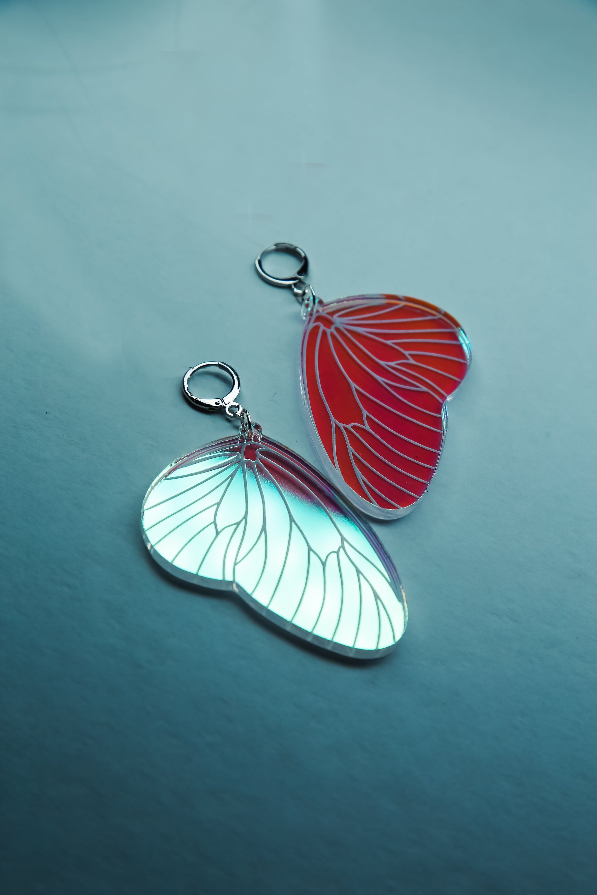 A flat lay of a pair of iridescent acrylic earring styled after a fairies wing