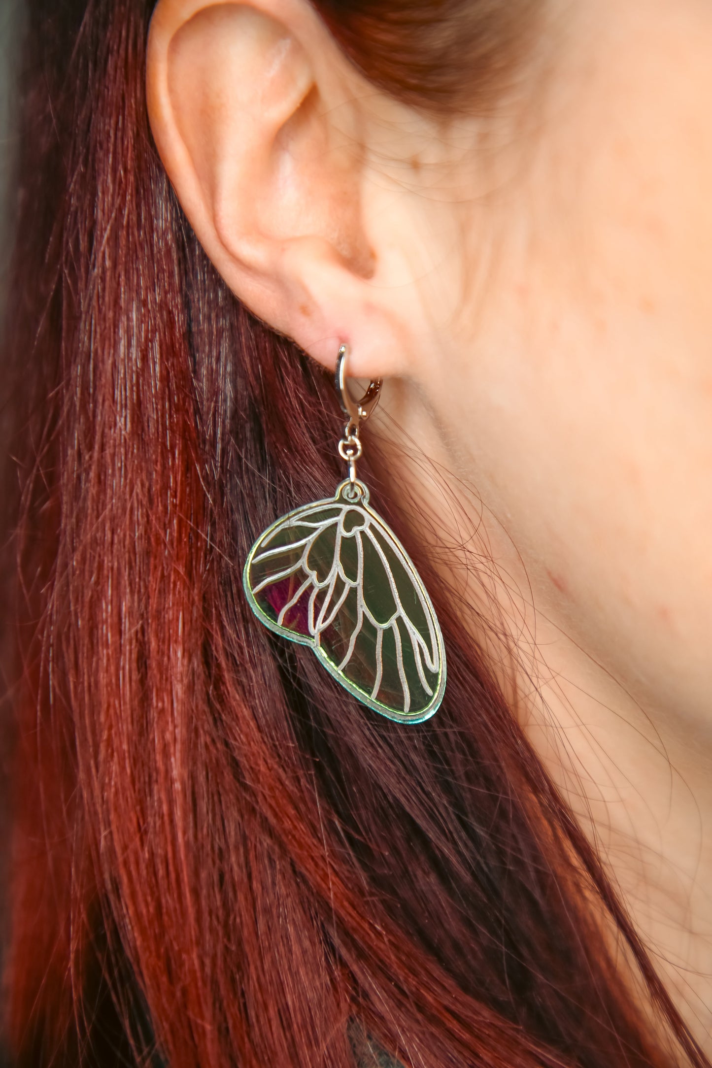 A mini iridescent acrylic earring  against brown hair
