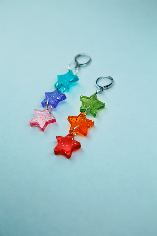 a flat lay of multicoloured glittery transparent star acrylic earrings