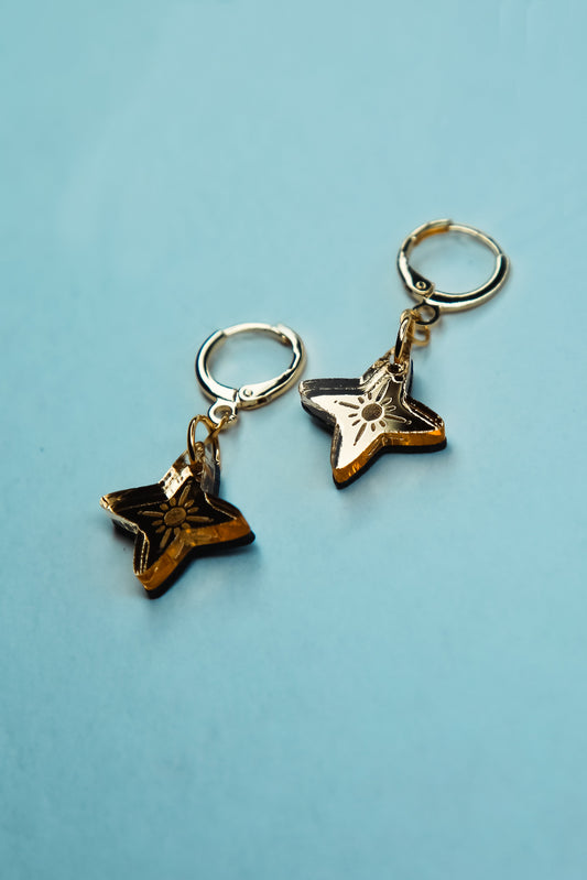 flat lay of a pair of star shaped acrylic earring made from reflective gold acrylic 