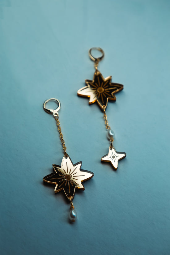 flat lay of star shaped acrylic earring made from reflective gold acrylic with pearls dangling off