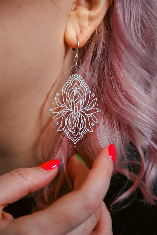 flower inspired acrylic earring made from transparent acrylic with a white design against pink hair