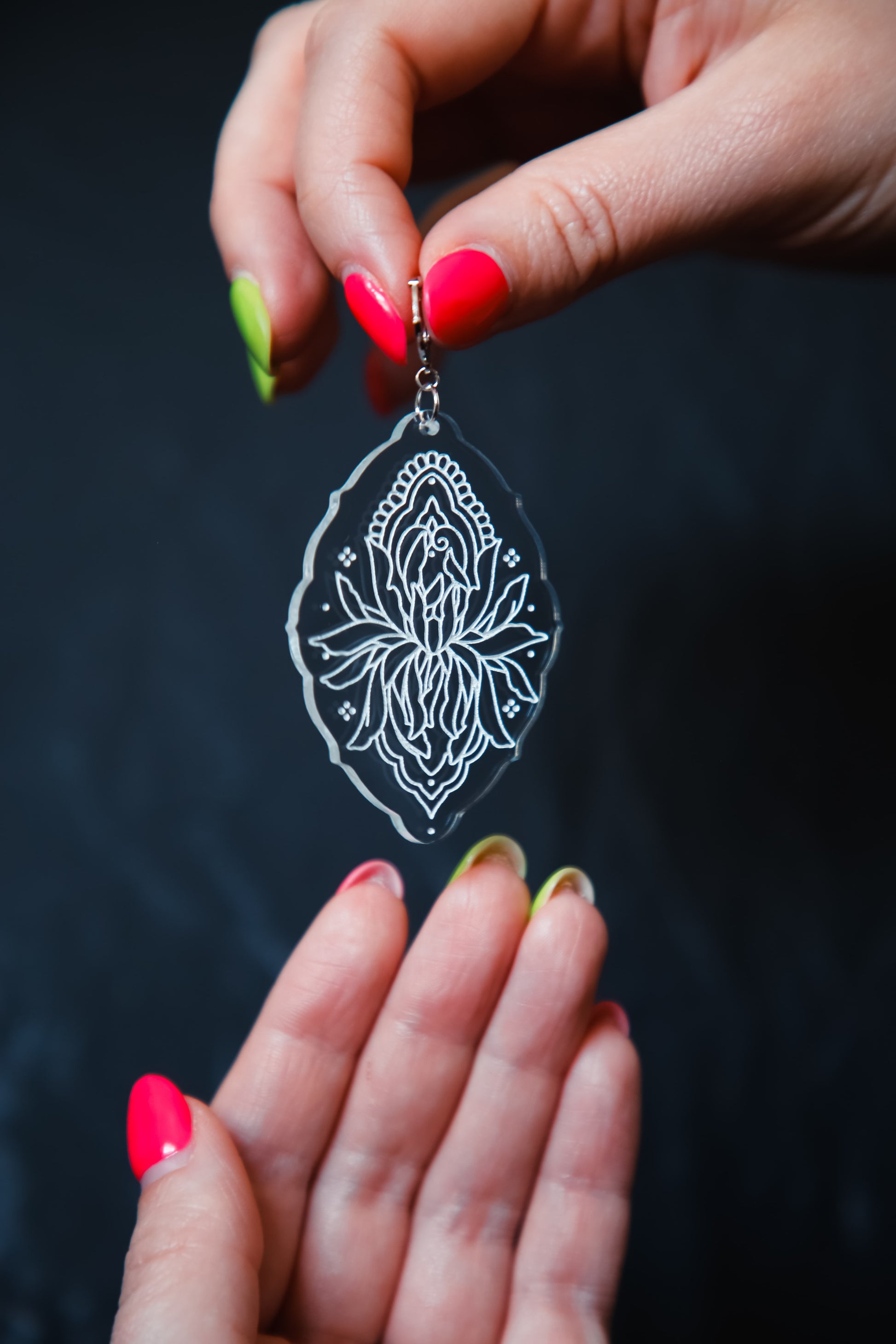 flower inspired acrylic earring made from transparent acrylic with a white design being held by hands