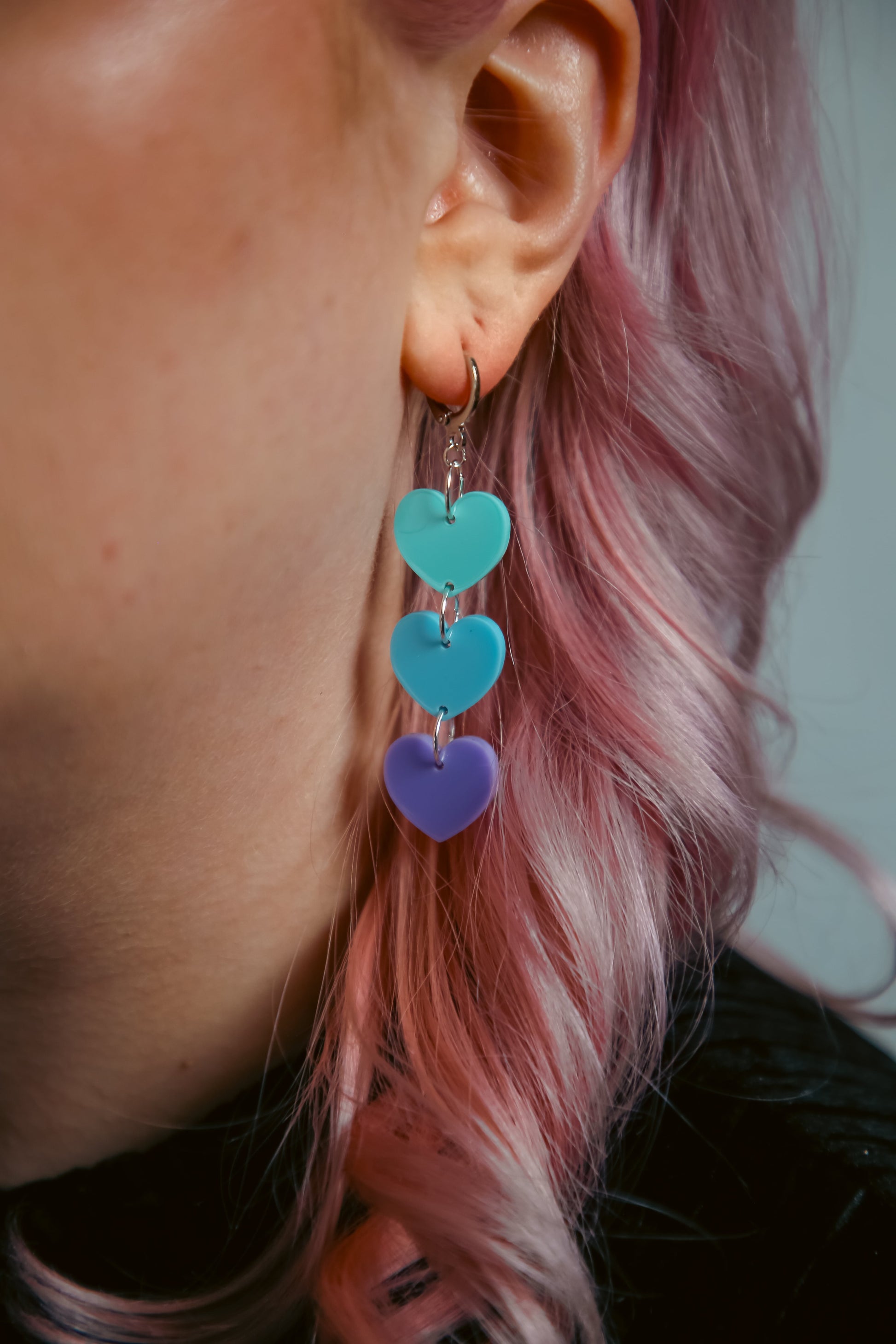 pastel cyan, blue and purple hearts acrylic earring against pink hair