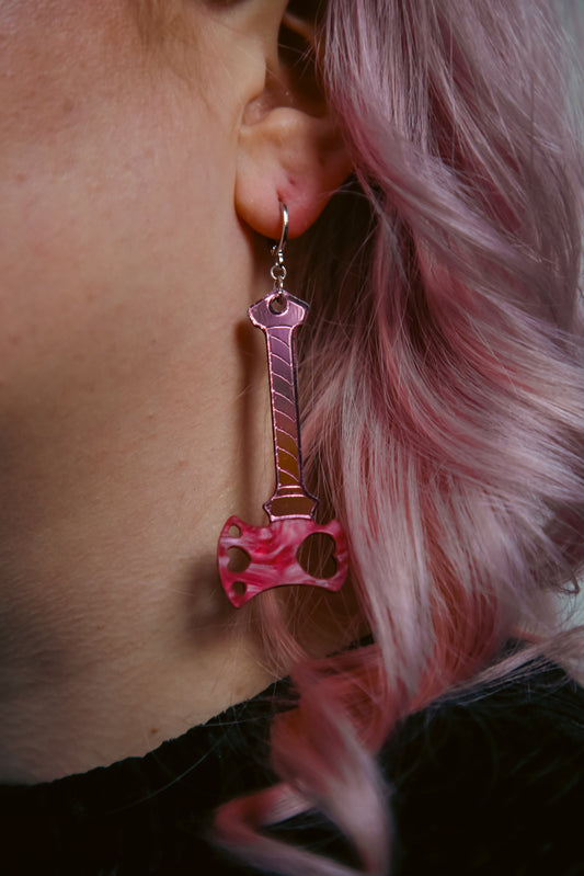 axe acrylic earring with pink blade and reflective pink handle against pink hair