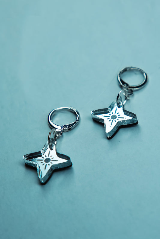 a pair of small silver star with reflective material against a blue background
