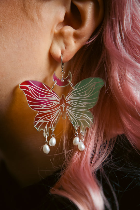 large butterfly iridescent acrylic earrings with pearls against pink hair