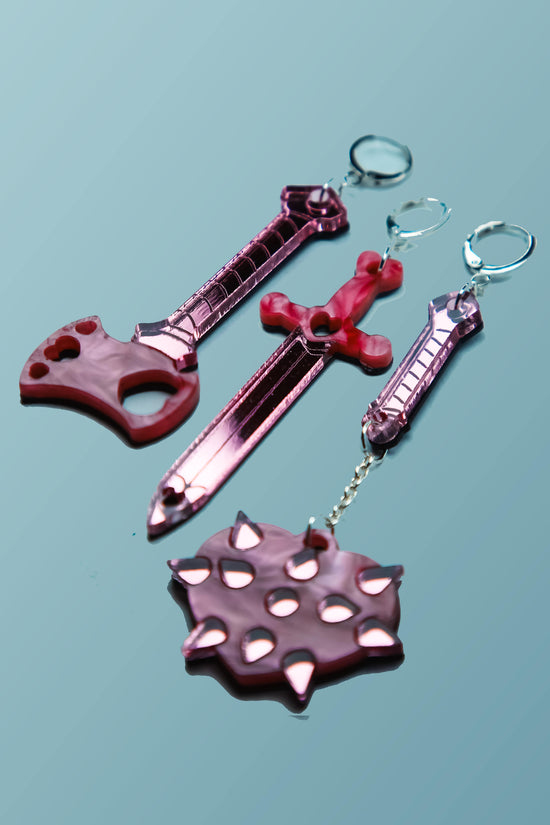 pink weapon acrylic earrings on a blue background